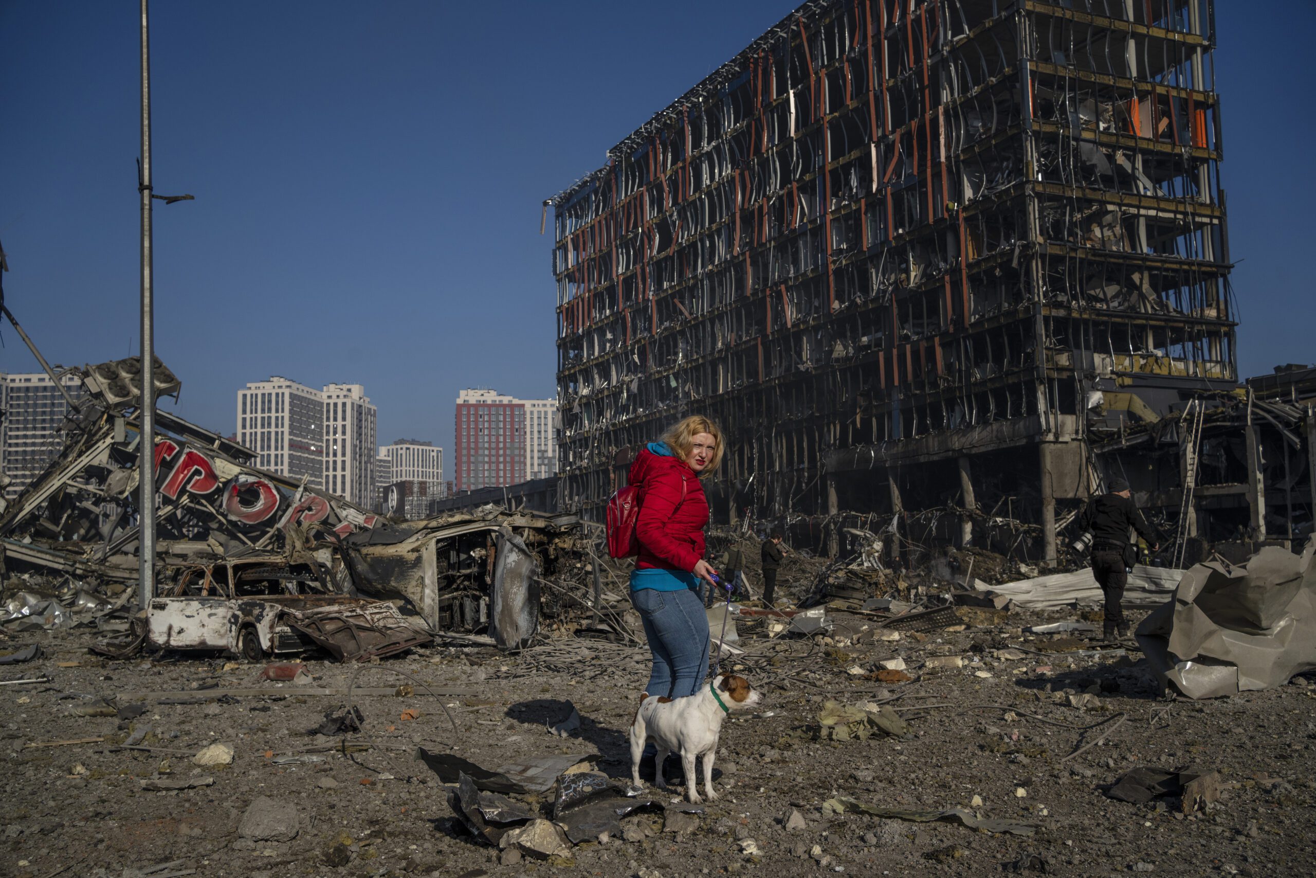 Irina Zubchenko walks with her dog Max amid the destruction caused after shelling of a shopping center, in Kyiv, Ukraine, Monday, March 21, 2022. (AP Photo/ (AP Photo/Rodrigo Abd)