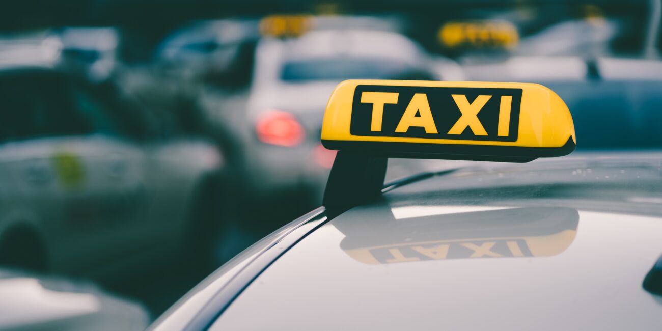 Selective focus shot of a yellow taxi sign in a traffic jam